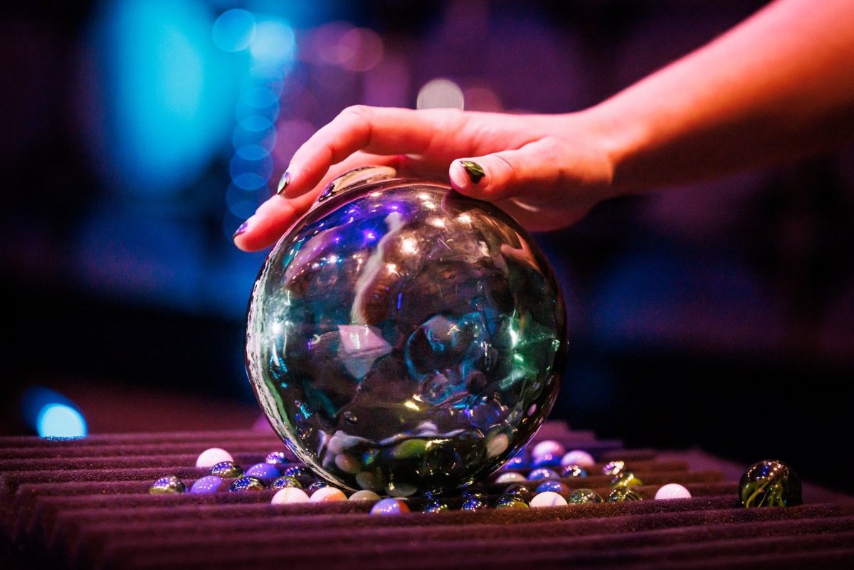 A percussionist's hand on a glass sphere resting among marbles during a performance of Dark Oceanography